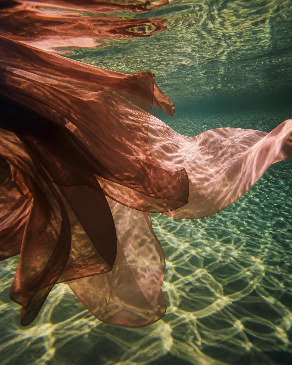 Dusty pink fabric flowing beneath clear water